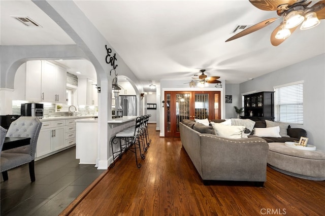 living room featuring ceiling fan, sink, and dark hardwood / wood-style floors