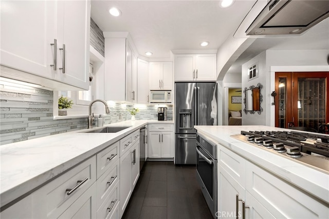 kitchen with sink, backsplash, stainless steel appliances, white cabinets, and light stone counters