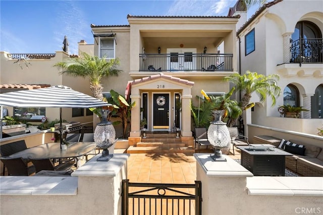 view of front of property featuring a patio, a balcony, a tiled roof, an outdoor living space, and stucco siding