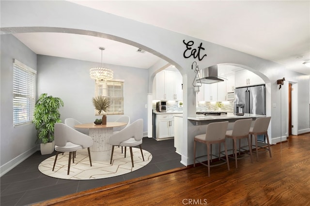 kitchen with wall chimney exhaust hood, white cabinets, high end fridge, and light countertops