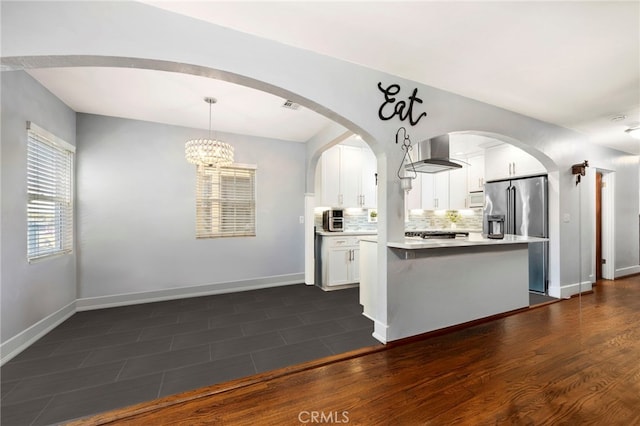 kitchen featuring wall chimney range hood, white cabinetry, light countertops, and high end fridge