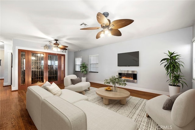 living area featuring baseboards, visible vents, wood finished floors, and a glass covered fireplace