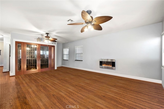 unfurnished living room featuring baseboards, visible vents, wood finished floors, and a glass covered fireplace