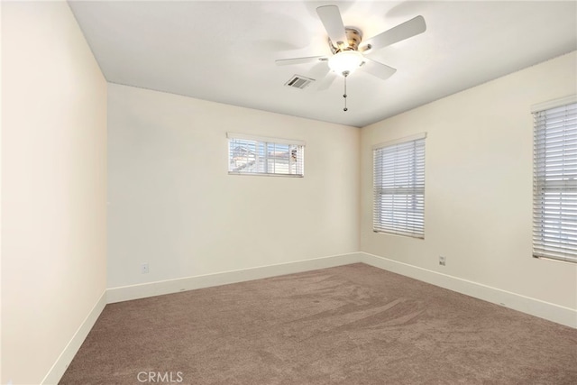 carpeted empty room with baseboards, visible vents, and a ceiling fan