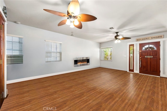 unfurnished living room featuring visible vents, a glass covered fireplace, wood finished floors, cooling unit, and baseboards