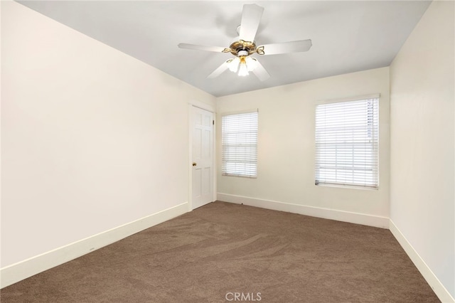 spare room featuring a ceiling fan, dark carpet, and baseboards