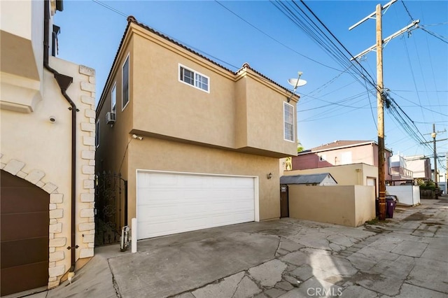 exterior space featuring an attached garage, fence, and stucco siding