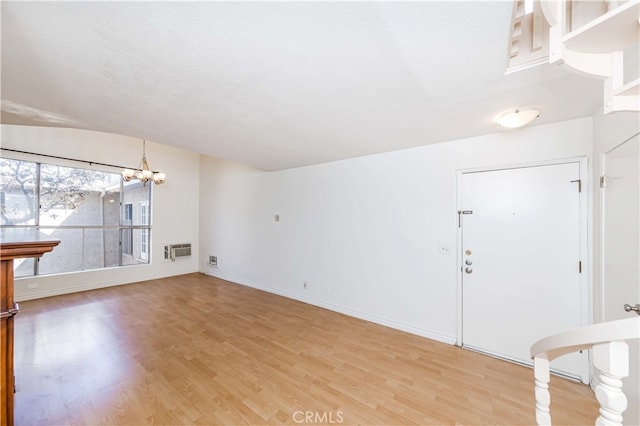 interior space featuring a wall unit AC, a notable chandelier, hardwood / wood-style floors, and a textured ceiling