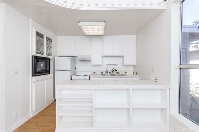 kitchen with light hardwood / wood-style flooring, kitchen peninsula, sink, white cabinets, and white appliances