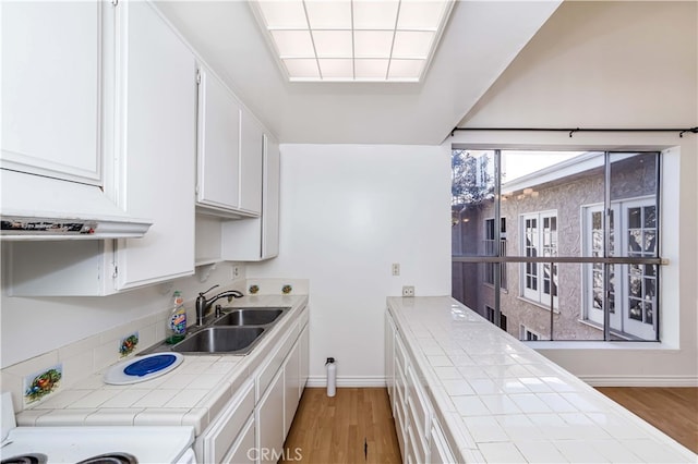 kitchen featuring white cabinetry, sink, light hardwood / wood-style flooring, and tile counters