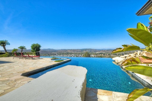 view of pool featuring a patio and a water and mountain view