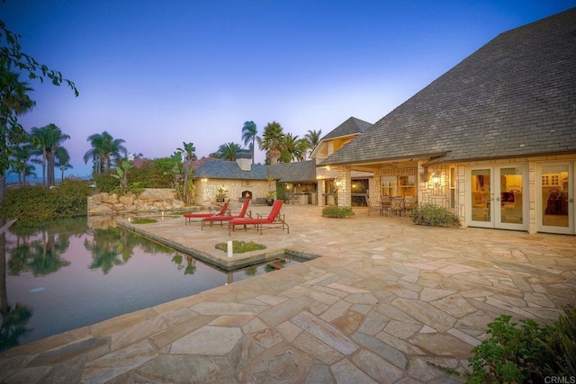 pool at dusk with a patio and french doors