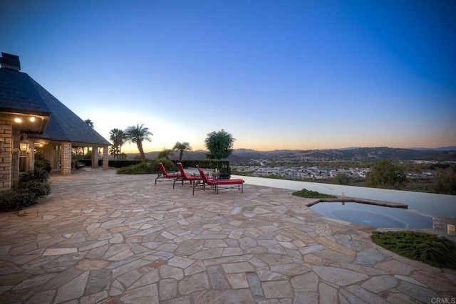 patio terrace at dusk featuring an in ground hot tub