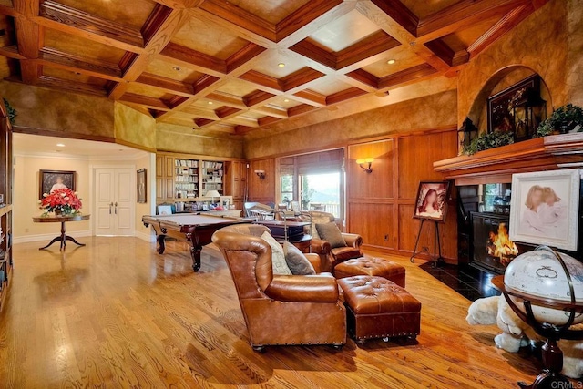 living room featuring beamed ceiling, light hardwood / wood-style floors, ornamental molding, and coffered ceiling