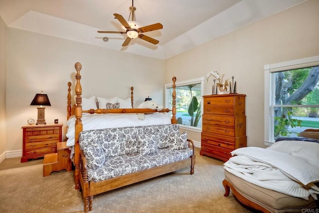 bedroom featuring a tray ceiling, multiple windows, and ceiling fan