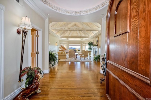 foyer entrance featuring beamed ceiling, wood-type flooring, ornamental molding, and coffered ceiling