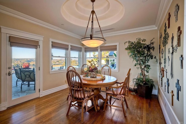 dining space with wood-type flooring, a tray ceiling, and crown molding