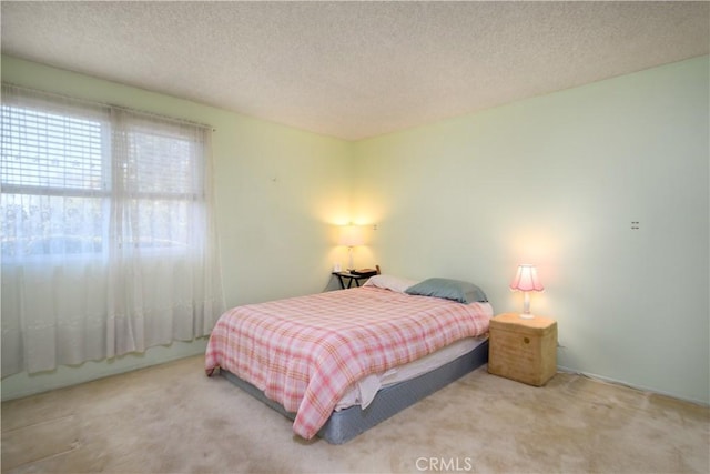 bedroom with light colored carpet and a textured ceiling