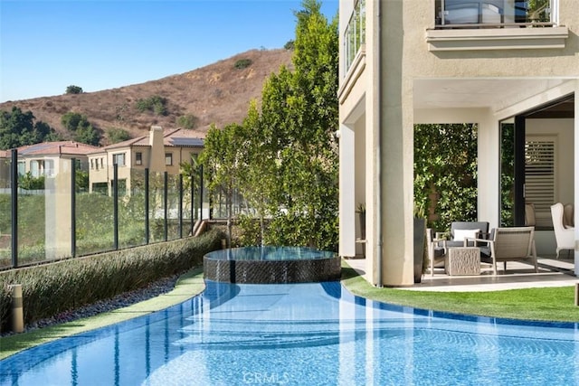 view of swimming pool with an outdoor hot tub, an infinity pool, a patio area, a mountain view, and outdoor lounge area