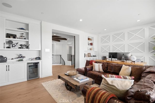 living room featuring recessed lighting, beverage cooler, light wood-style floors, built in features, and a bar