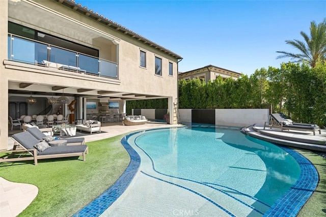 pool with an outdoor kitchen, an outdoor hangout area, and a patio