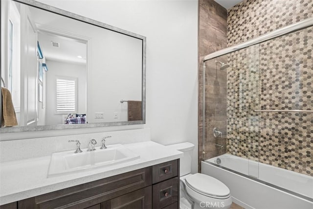 full bathroom with shower / bath combination with glass door, vanity, and toilet