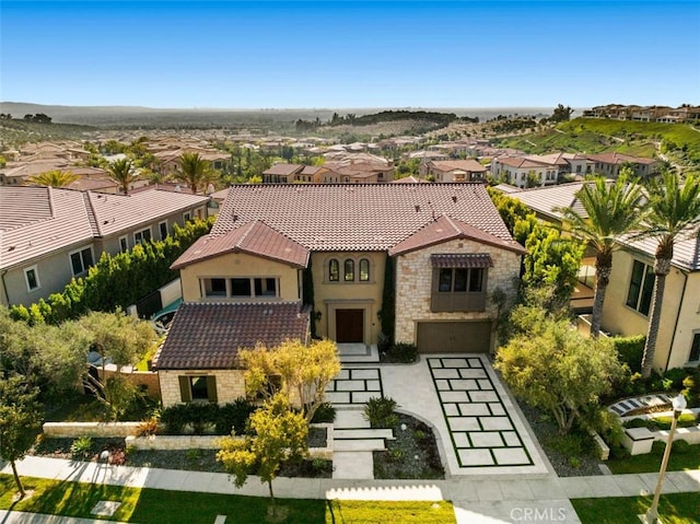 mediterranean / spanish home with a residential view, stone siding, a tiled roof, and stucco siding