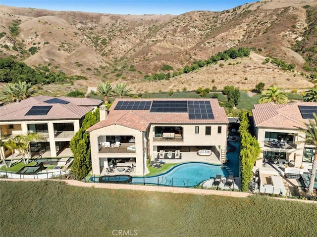 rear view of property with a chimney, roof mounted solar panels, and a mountain view