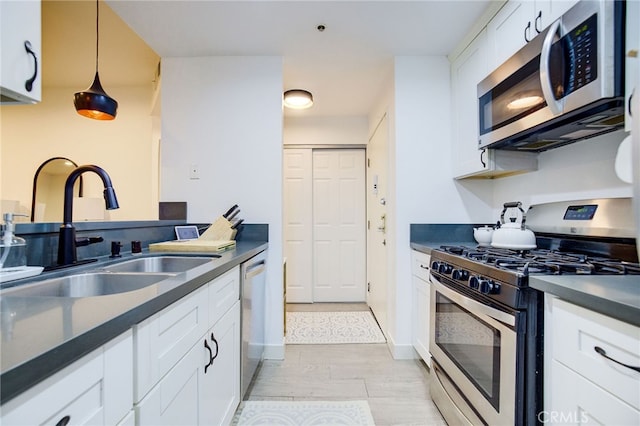 kitchen with sink, light wood-type flooring, stainless steel appliances, decorative light fixtures, and white cabinets