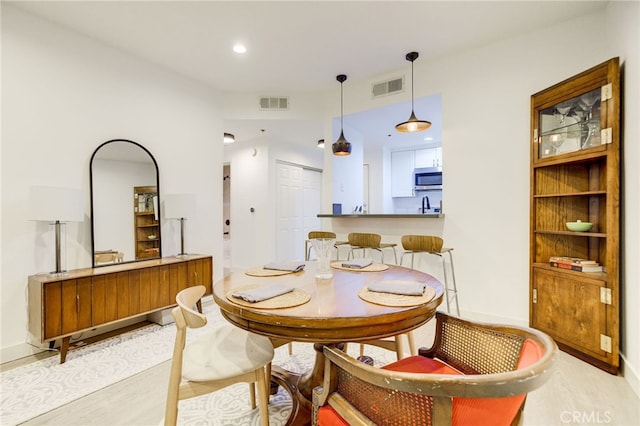 dining area with light hardwood / wood-style floors and sink