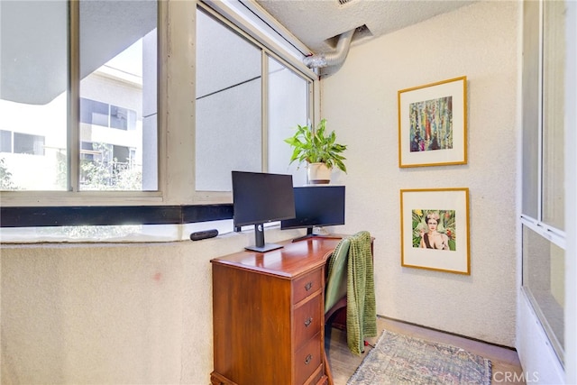 home office with a textured ceiling and hardwood / wood-style flooring