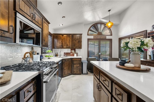 kitchen featuring appliances with stainless steel finishes, tasteful backsplash, dark brown cabinets, decorative light fixtures, and lofted ceiling