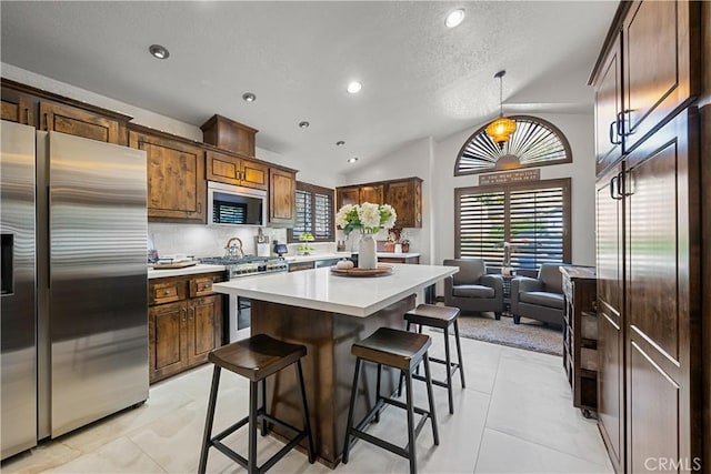 kitchen featuring a center island, stainless steel appliances, pendant lighting, lofted ceiling, and a kitchen bar