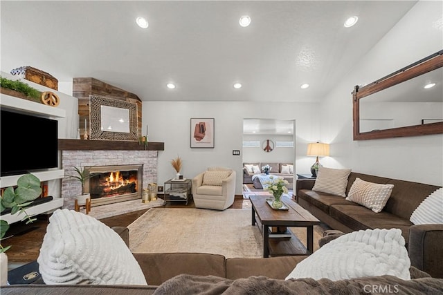 living room with wood-type flooring, a large fireplace, and vaulted ceiling