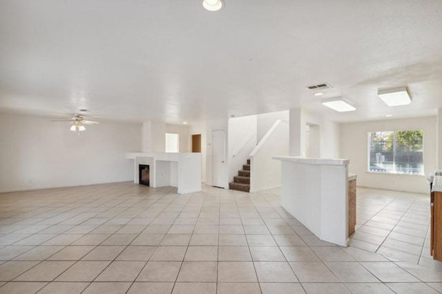 unfurnished living room featuring light tile patterned floors and ceiling fan