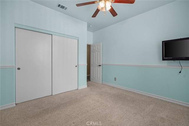 unfurnished bedroom with ceiling fan, a closet, and light carpet