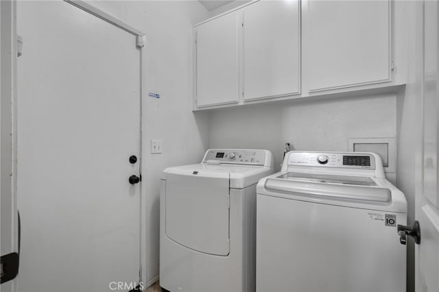 clothes washing area featuring cabinets and washing machine and clothes dryer