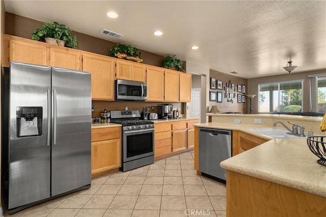 kitchen with appliances with stainless steel finishes, light tile patterned floors, light brown cabinetry, and sink