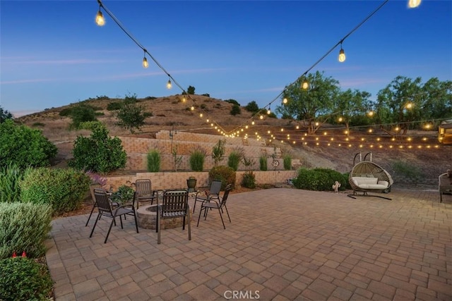 patio terrace at dusk featuring a mountain view and an outdoor fire pit