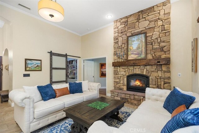 45600 La Cruz Dr, Temecula, CA 92590 - living area featuring crown molding, arched walkways, wood finished floors, a stone fireplace, and a barn door