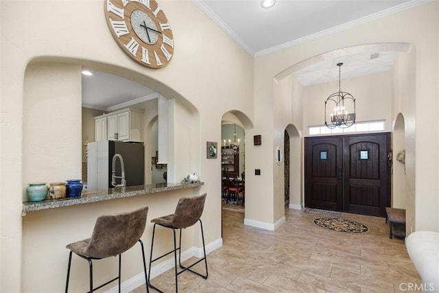 entryway featuring a notable chandelier, a towering ceiling, and crown molding