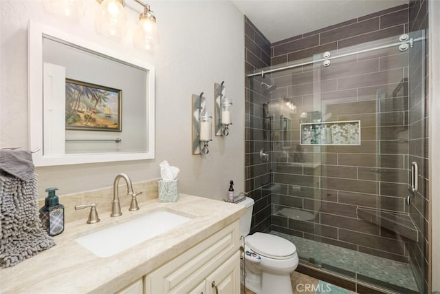 bathroom with vanity, toilet, and a shower with door