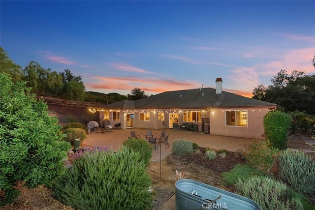 back house at dusk featuring a patio area