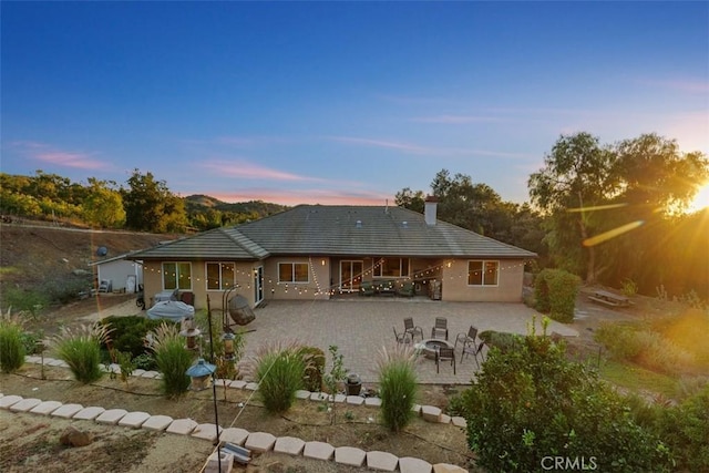 back house at dusk featuring a patio and an outdoor fire pit