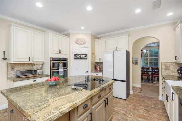 kitchen with white cabinetry, stainless steel double oven, white fridge, decorative backsplash, and a kitchen island