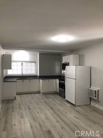 kitchen featuring sink, black range, light hardwood / wood-style floors, and white refrigerator