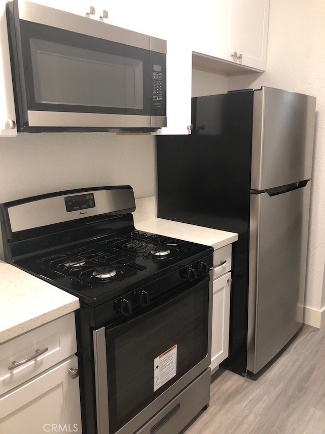 kitchen with white cabinetry, appliances with stainless steel finishes, and light wood-type flooring