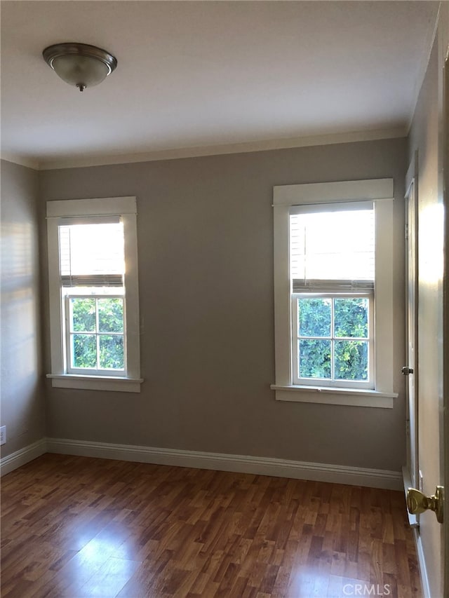 unfurnished room featuring ornamental molding and dark wood-type flooring