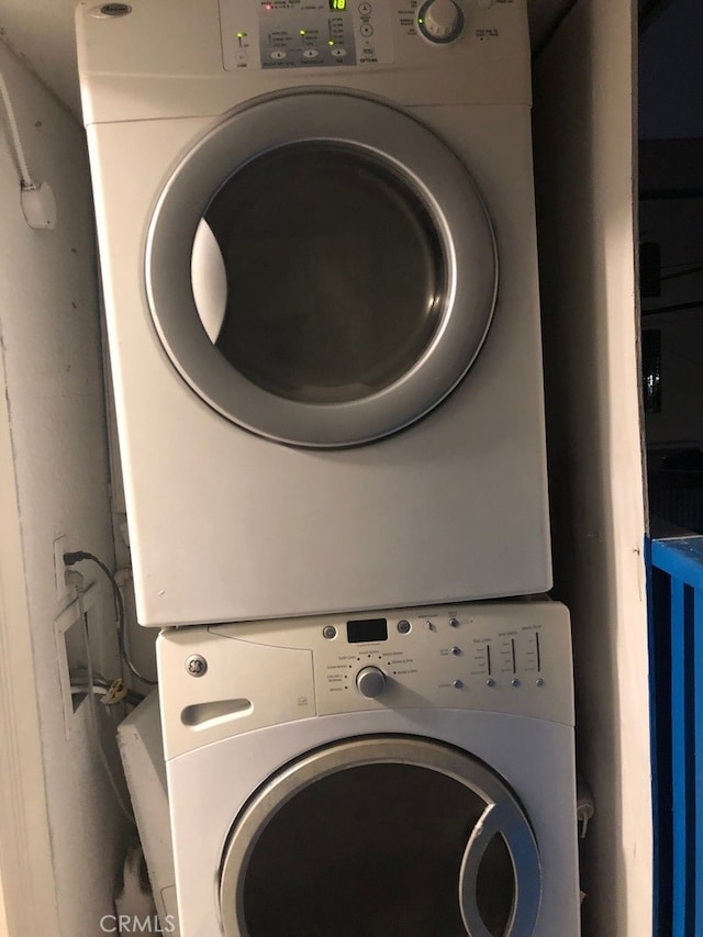 clothes washing area with stacked washer / dryer