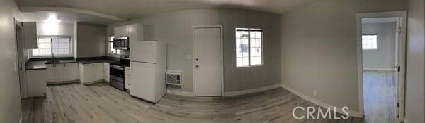 kitchen with light hardwood / wood-style flooring, white cabinetry, heating unit, and range with electric cooktop